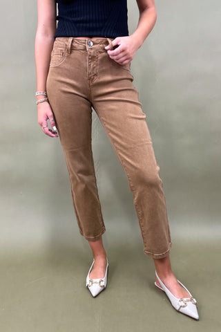 Person wearing brown pants and white shoes on a plain background