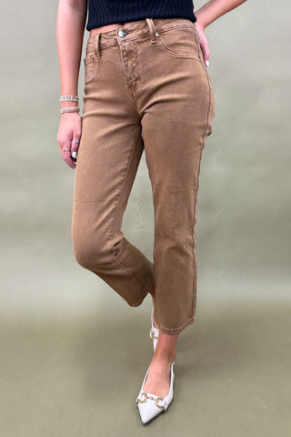 Person wearing brown pants and white shoes on a plain background