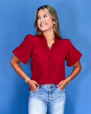 Woman wearing a red blouse and blue jeans against a blue background