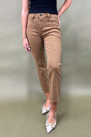 Person wearing brown pants and white shoes on a plain background