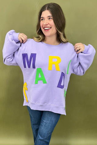 Woman wearing a purple sweatshirt with colorful letters against a green background