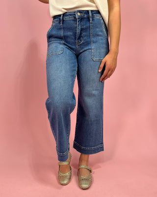 Person wearing blue jeans on a pink background