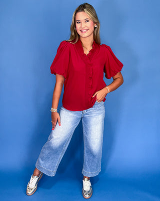 Woman wearing a red blouse and blue jeans against a blue background