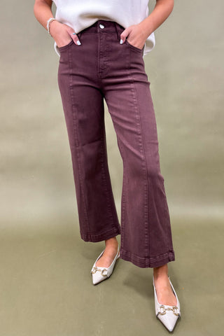 Person wearing purple pants and white shoes on a beige background