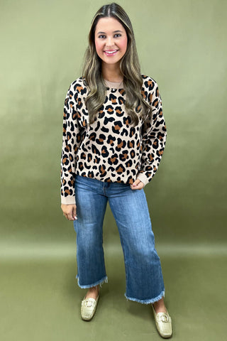 Woman wearing a leopard print top and blue jeans against a green background