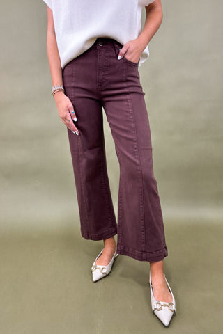 Person wearing maroon pants and white shoes on a plain background