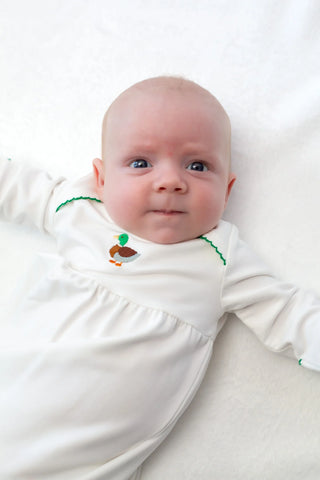 Baby wearing a white outfit with green accents on a white background