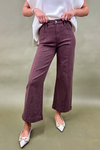 Person wearing maroon pants and white top on a plain background