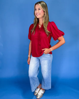 Woman wearing a red blouse and blue jeans against a blue background