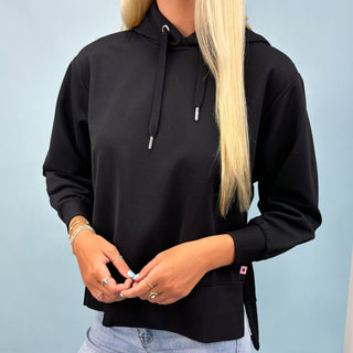 Person wearing a black hoodie with a light blue background