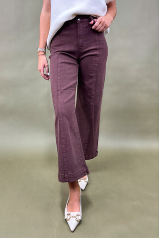 Person wearing purple pants and white shoes on a plain background