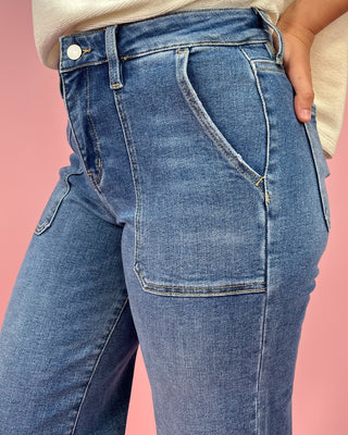 Blue jeans worn by a person on a pink background