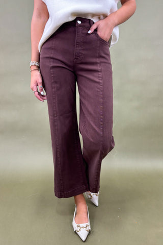 Person wearing maroon wide-leg pants with a plain background