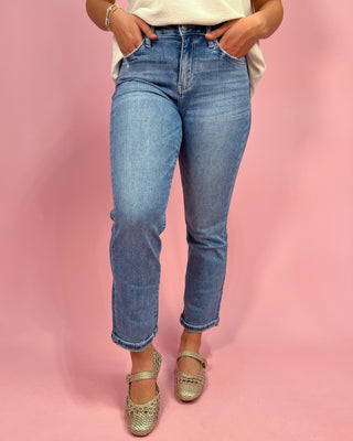 Person wearing blue jeans and sparkly shoes on a pink background
