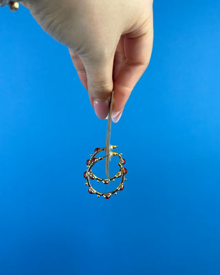 Shop the Rachel Red Stone Hoops featuring glossy red stones, polished gold-tone hoops, and delicate bead accents. Perfect for holidays and game days.