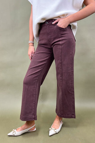 Person wearing maroon pants and white top on a plain background