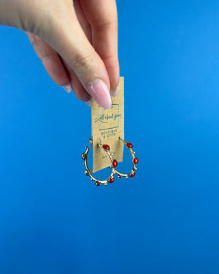 Shop the Rachel Red Stone Hoops featuring glossy red stones, polished gold-tone hoops, and delicate bead accents. Perfect for holidays and game days.