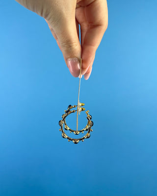 Shop the Kristi Black Stone Hoops featuring glossy black stones, polished gold-tone hoops, and delicate bead accents. Perfect for everyday elegance.