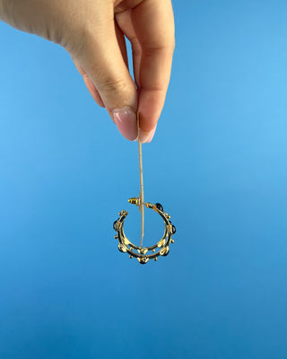 Shop the Kristi Black Stone Hoops featuring glossy black stones, polished gold-tone hoops, and delicate bead accents. Perfect for everyday elegance.