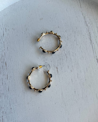 Shop the Kristi Black Stone Hoops featuring glossy black stones, polished gold-tone hoops, and delicate bead accents. Perfect for everyday elegance.