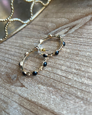 Shop the Kristi Black Stone Hoops featuring glossy black stones, polished gold-tone hoops, and delicate bead accents. Perfect for everyday elegance.