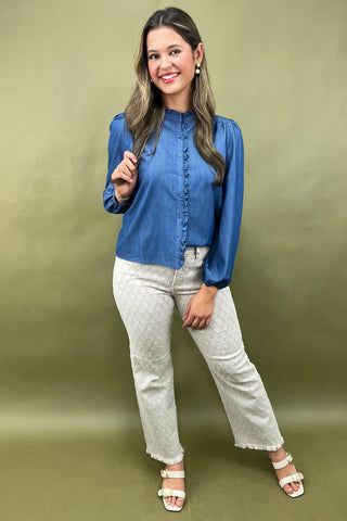 Woman wearing a blue blouse and white pants against a green background