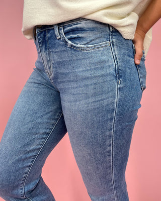 Person wearing blue jeans against a pink background