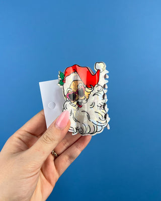 Shop the Santa Hair Clip featuring a pearlescent Santa design, pink heart sunglasses, and festive holiday details. A cute Christmas claw clip!