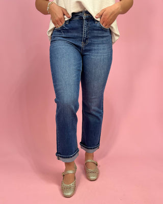Person wearing blue jeans and a white top on a pink background