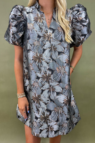 Woman wearing a floral dress with puff sleeves against a green background