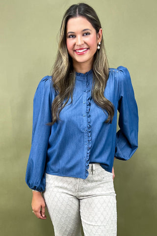 Woman wearing a blue blouse with long sleeves against a green background