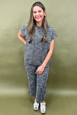 Woman wearing a gray knit outfit against a green background
