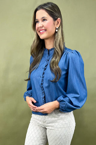 Woman wearing a blue blouse with long sleeves against a green background