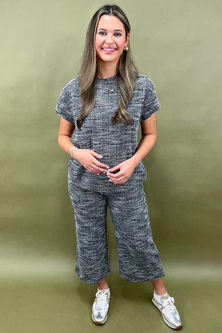 Woman wearing a gray knit outfit against a green background