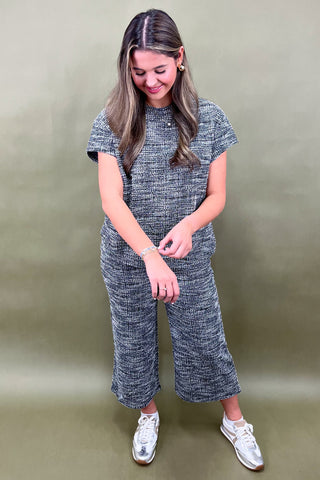 Woman wearing a textured jumpsuit against a plain background