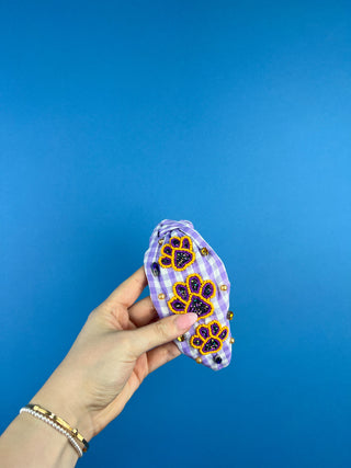 Shop the Purple Gingham Gameday Headband featuring sparkling purple and gold beaded paw prints, rhinestones, and a trendy knotted design. Perfect for game day!
