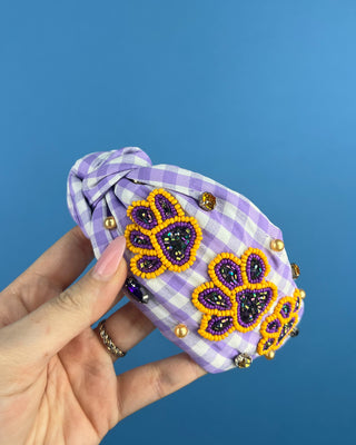 Shop the Purple Gingham Gameday Headband featuring sparkling purple and gold beaded paw prints, rhinestones, and a trendy knotted design. Perfect for game day!