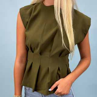 Person wearing an olive green sleeveless top against a light blue background