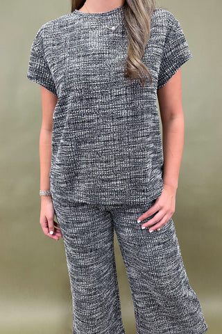 Person wearing a black and white patterned outfit against a beige background