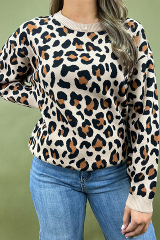 Person wearing a leopard print sweater and blue jeans against a green background