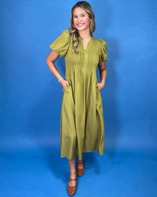 Olive green maxi dress with a V-neckline, pintuck detailing, short puff sleeves, and a flowy silhouette.