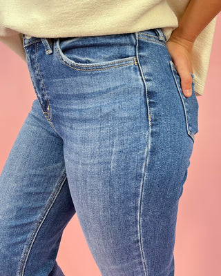 Blue jeans worn by a person on a pink background