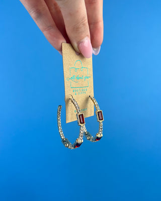 Shop the Gabi Red Stone Hoops featuring gold-tone hoops, sparkling clear rhinestones, and rich red rectangular stones. Perfect for holidays and everyday style!
