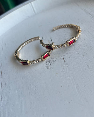 Shop the Gabi Red Stone Hoops featuring gold-tone hoops, sparkling clear rhinestones, and rich red rectangular stones. Perfect for holidays and everyday style!