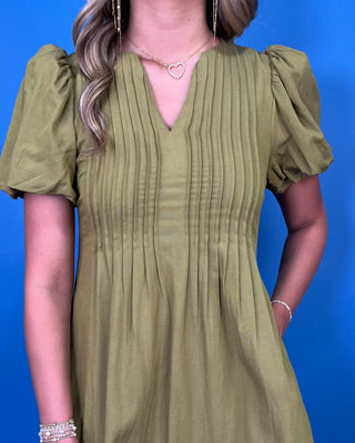 Olive green maxi dress with a V-neckline, pintuck detailing, short puff sleeves, and a flowy silhouette.