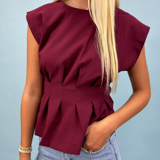 Maroon top worn by a person against a light blue background