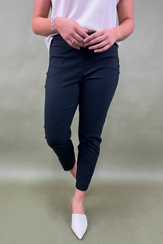 Person wearing navy pants and white shoes on a plain background