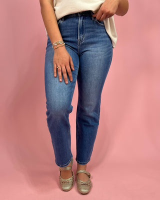 Person wearing blue jeans and gold shoes on a pink background