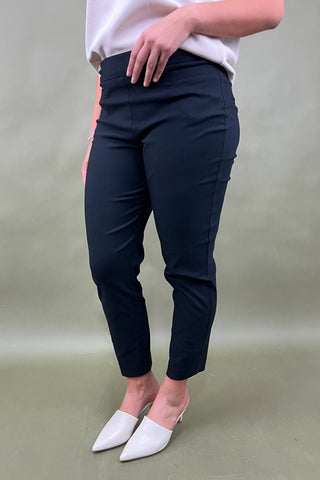 Person wearing navy pants and white shoes on a plain background