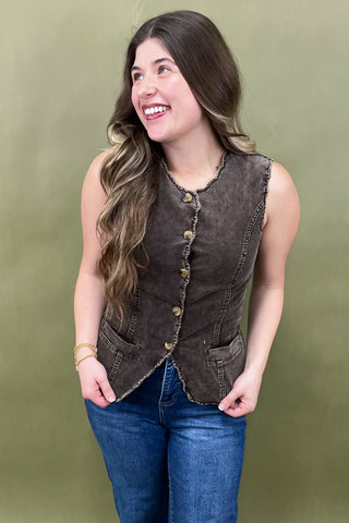Woman wearing a brown vest over a blue shirt against a green background
